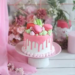Pretty in pink! This adorable drip cake is topped with colorful macarons and meringue kisses, making it a perfect centerpiece for a sweet and stylish birthday party.