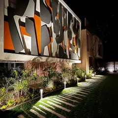 The interplay of the landscape lighting with the illuminated architectural facade creates a powerful dialogue between the building and its natural surroundings.