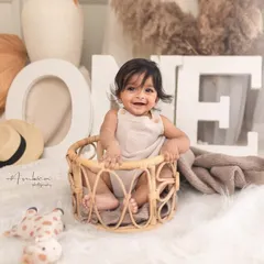This happy baby is celebrating his first year. The 'ONE' sign and simple, neutral props keep the focus on his infectious smile and bright eyes.