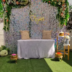 An "Oh Baby" sequin backdrop for a baby shower. The shimmering wall, combined with a floral garland and a simple bench, creates a beautiful and celebratory photo spot.