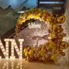 Welcome your guests in style with this beautiful crescent-shaped balloon arrangement. The mix of yellow, white, and gold chrome balloons, along with a "Welcome" neon sign and marquee letters, creates a warm and impressive entrance for anniversaries, baby showers, or welcome home parties.