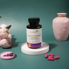 An elegant and clean shot of women's multivitamin capsules. The soft lighting and props like a pink vase and flowers create a gentle and feminine aesthetic.