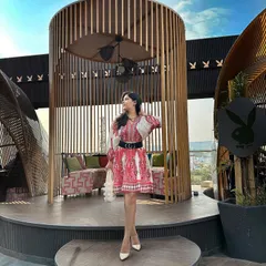 The full look of the red and white printed dress, styled for a sunny day on a rooftop. The wide belt cinches the waist, creating a flattering silhouette that's perfect for a day event.