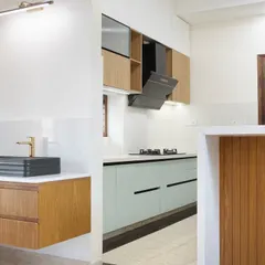 This shot shows the relationship between the kitchen and the separate wash area. The floating vanity with its modern black basin is framed by wood, echoing the kitchen's materials and creating a cohesive design story throughout the space.