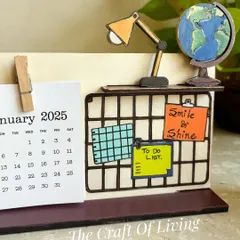 A closer look at the "Smile & Shine" desk calendar. The miniature desk, lamp, and globe add a whimsical and motivational touch to your workspace.