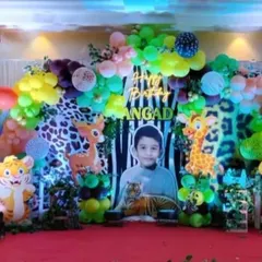 A full-scale jungle adventure for a 5th birthday. This stage decoration is filled with friendly animal cutouts like lions, tigers, and elephants, set against a lush backdrop with a personalized photo of the birthday boy to make him the king of the jungle.