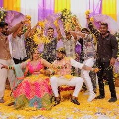 The 'Phoolon ki Holi' in full swing! The couple is showered with marigold petals by their friends and family, creating a moment of pure, unadulterated joy.