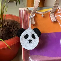 The panda pouch hanging from a tote bag, demonstrating how it can be used as a cute bag charm.