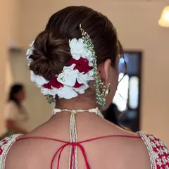 This bridal bun combines red and white flowers for a classic and vibrant look. The flowers are carefully placed around a neatly twisted bun, creating a beautiful frame that complements the traditional red and white wedding attire.