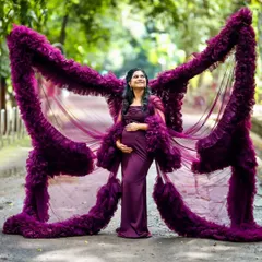 Feel like a goddess in my signature butterfly-effect maternity gown. The dramatic ruffled wings create a stunning silhouette that celebrates your journey to motherhood. This deep purple gown is a favorite for outdoor maternity shoots, adding a touch of royalty and magic.