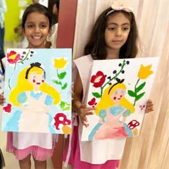 Two best friends proudly showing off their finished Alice paintings. Art parties are a wonderful way for kids to bond and create something special together.