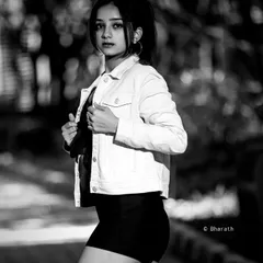 A full-length black and white portrait on a paved path. The strong lines and contrast create a bold, graphic image.