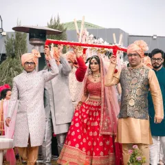 The bride's grand entrance under a beautiful phoolon ki chadar, held by her brothers. This is a classic and emotional moment from an Indian wedding.