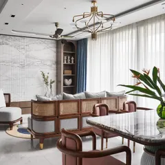 A view of the living room highlighting the custom-designed sofa and lounge chairs, which blend wood and cane for a rustic, Zen-like feel. The fluted Satvario marble TV unit wall adds a touch of opulence and visual height.
