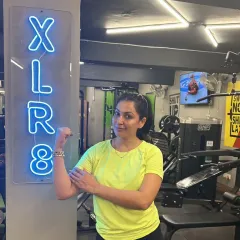 A happy and strong client posing next to our XLR8 sign. This is the result of hard work and a positive environment.
