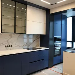 A modern kitchen design featuring a bold combination of navy blue and white cabinets. The marble-patterned backsplash and integrated appliances create a seamless and sophisticated look.