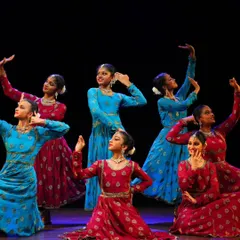 My talented students from the Sāttvatī School of Dance in a dynamic pose during our "ARAMBH" performance, dressed in vibrant red and blue costumes.