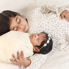 The quiet moments are often the most powerful. Here, an older sister peacefully rests beside her new sibling, a simple and beautiful portrait of their developing bond.