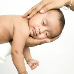A baby sleeping peacefully, cradled in their parent's hands. This shot emphasizes the contrast in size and the feeling of complete safety and trust.