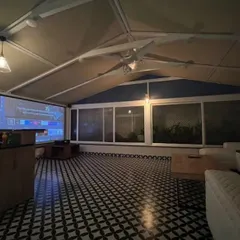 A stylish and functional sunroom on a terrace, designed for Mr. Amar Nagaram. This space features striking Moroccan tiled flooring and retractable remote-controlled blinds, making it a perfect home theater or lounge area.