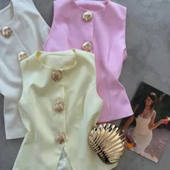 A flat-lay of my sleeveless waistcoats in off-white, pink, and pale yellow. Each one features beautiful seashell-inspired gold buttons for a unique touch.