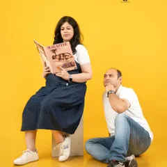 A playful scene where the dad-to-be looks on dreamily as his partner reads a magazine. This lighthearted concept adds a fun, narrative element to your couple's photoshoot.