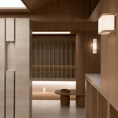 A choreography of light, material, and proportion at Be Well. This view shows the seamless transition between spaces, marked by subtle shifts in texture from smooth stone to ribbed wood.