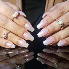 A classic and elegant manicure featuring a sheer, pearly white polish on long, square-shaped nail extensions.