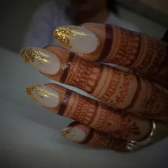A classic and elegant bridal nail design. This set features a soft white base with a touch of gold leaf at the tips, creating a look that pairs beautifully with traditional henna.