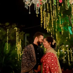 Standing under a beautiful chandelier and fairy lights, the couple shares a happy, intimate moment, their smiles lighting up the night.