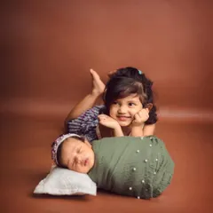 The sweetest sister duo. An older sister proudly watches over her new baby sibling, a precious memory of their first days together.