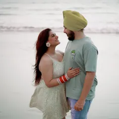 A candid moment of connection. The couple shares a look, lost in their own world, with the gentle waves of the sea behind them. This is what relaxed destination photography is all about.