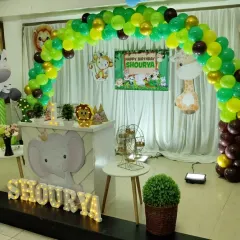 A side view of the jungle safari birthday setup. This shows the custom elephant-themed counter, light-up name, and how the balloon arch creates a perfect frame for the stage.