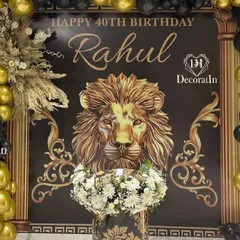 A bold and regal 40th birthday setup featuring a lion theme on a black and gold backdrop. The design is framed by a dramatic balloon arch and includes a custom-designed pedestal for the cake, perfect for a king.