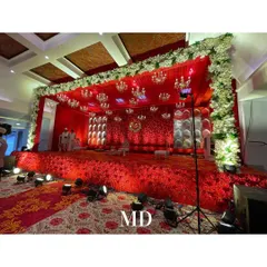 A side view of the opulent red-themed engagement stage. The stage is elevated and covered in red flowers, framed by a border of white blooms, making it a stunning focal point.