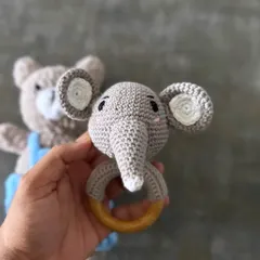 This elephant rattle is designed to be both cute and functional for a baby. It's handcrafted from pure cotton yarn with embroidered eyes and is attached to a high-quality, smooth wooden ring for teething.