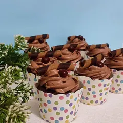 A batch of my classic chocolate cupcakes. Each one is topped with a swirl of rich chocolate frosting, a chocolate-covered coffee bean, and a decorative chocolate wafer roll.