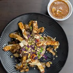 A plated meal of grilled chicken strips over a bed of seasoned rice and vegetables, with a side of sauce. This dish is a great example of a clean and satisfying post-workout meal.