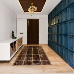 Another view of the foyer, highlighting the striking blue paneled wall that conceals storage. The design balances bold color with the warmth of wood and the elegance of marble.