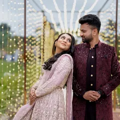 A romantic couple posing at their Sangeet against a backdrop of fairy lights, creating a magical and dreamy atmosphere.