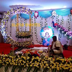 This is a popular naming ceremony stage design featuring a large crescent moon swing made of fresh flowers. The peacock motif and baby's photo add a personal touch to the celebration.