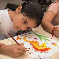 A student carefully adds details to her seahorse painting. This project helps develop fine motor control and an understanding of color gradients.
