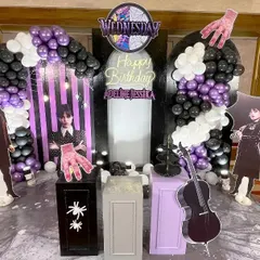 A closer look at the 'Wednesday' party setup, focusing on the central backdrop with character cutouts and detailed props. The arrangement includes spiderweb details and themed plinths for a complete, immersive experience.