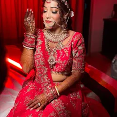 A candid moment of the bride, showcasing her dreamy red lehenga and the ethereal glow of her makeup. This look was a labor of love, designed to tell her unique story.