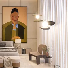 This calm bedroom is defined by earthy tones and clean lines. A large, expressive portrait provides a splash of color and character, while the minimalist furniture and sheer curtains maintain a light, airy feel.