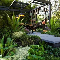 This lush garden design transforms a backyard or large terrace into a tropical retreat. We used dense, layered planting, a stone walkway, and a covered seating area with modern pendant lighting to create a secluded and functional space.