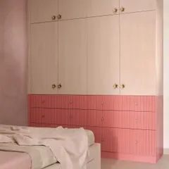 This full-height wardrobe combines fluted pink drawers with light wood-finish doors, accented with charming gold knobs. It's a design that is both whimsical and practical, providing ample storage that can grow with the child.