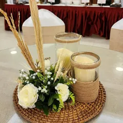 The details matter. This is a close-up of a bohemian-themed table centerpiece I created. It features candles in jute-wrapped holders, sprigs of wheat, and simple white flowers on a woven rattan mat, perfectly capturing the rustic and natural aesthetic.