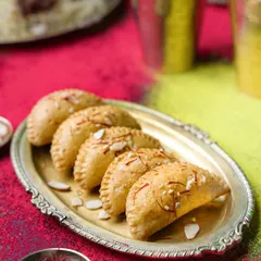 A festive shot for a biryani brand's Holi campaign. The colorful background and traditional silver platter make the gujiyas look celebratory and delicious, perfectly aligning with the festival's spirit.