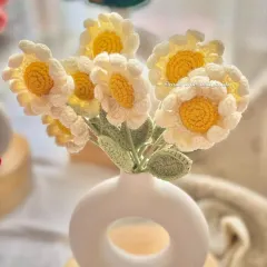A close-up of the daisy bouquet. You can see the texture of the petals and the bright yellow centers, all made by hand with yarn.